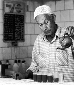 An old mak in Algeria poring mint tea in a cafe