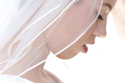Bride looking down wearing white transparent vail