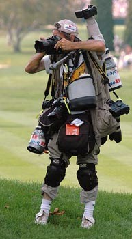 A wedding photographer carrying numerous cameras