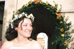 A bride wearing a flower tiara with wedding flowers in the background