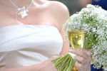 Bride holding a glass of Champaign and a bouquet of flowers