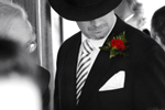 Groom with hat looking at a red rose