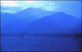 Blue image of Srinagar lake with mountains in the background
